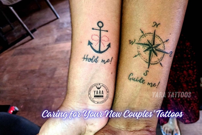 Matching anchor and compass couples' tattoos with 'Hold me!' and 'Guide me!' inscriptions, designed by Yaara Tattoos in Coimbatore. These tattoos symbolize love, direction, and support. Visit Yaara Tattoos in Coimbatore for personalized couples' tattoo designs and expert aftercare tips