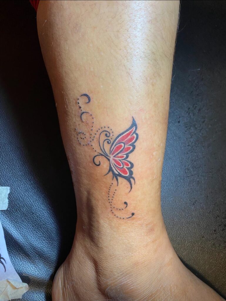 The image shows a beautiful butterfly tattoo in black and red.