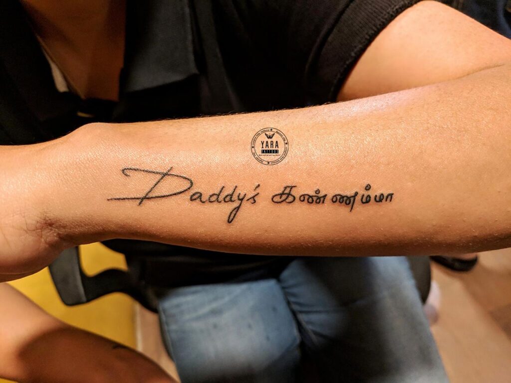The image shows a lettering tattoo “Daddy’s Kannamma" in a simple hand-written style.