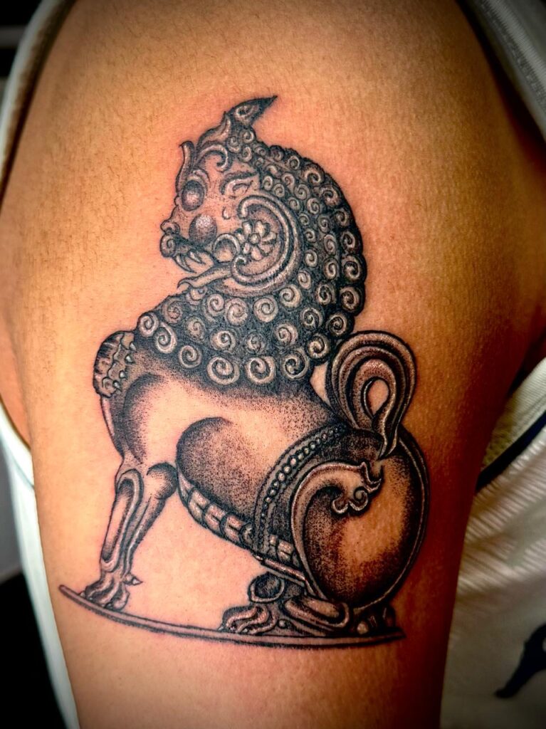 The image shows a tattoo of a traditional Yali (mythical lion-like creature) with intricate shading and ornamental detailing inspired by South Indian temple art.