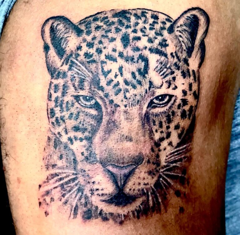 The image shows a detailed realistic black and grey tattoo of a leopard’s face.