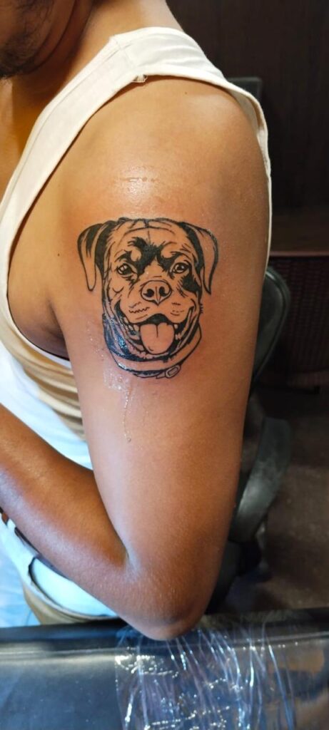 The image shows a realistic portrait tattoo of a dog in black and grey shade.