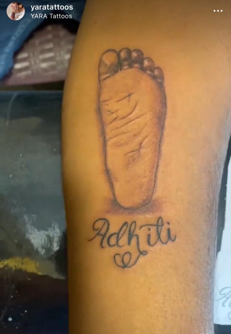 The image shows a detailed portrait tattoo of a child’s feet and the name “Adhiti” written below.