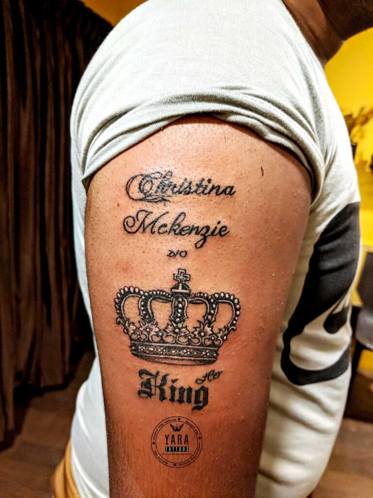 Arm tattoo showing name text and crown design on clean prepared skin.